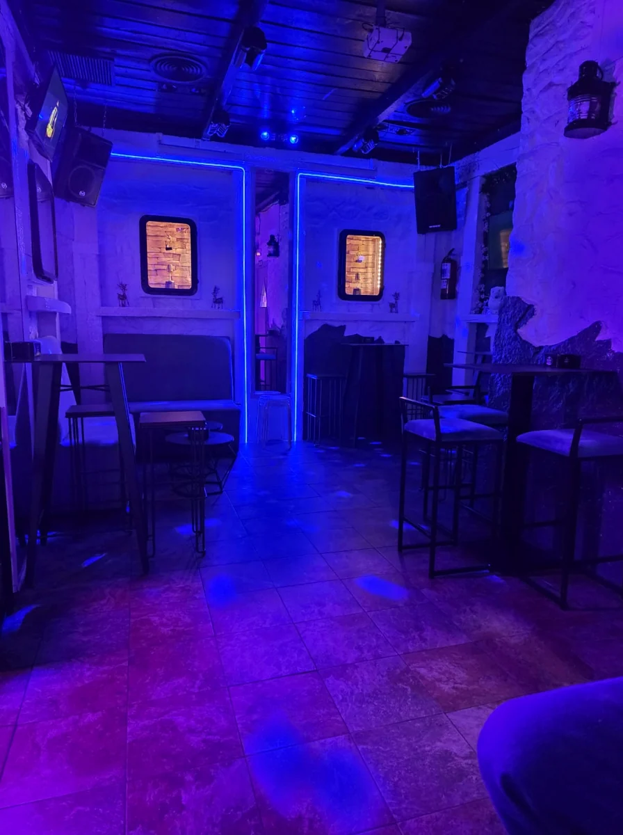 Sala de La Santa con mesas, asientos y luz azul y violeta.